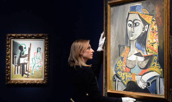 زنی در حال نصب نقاشی به دیوار گالری