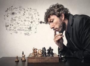 مردی که در مقابل صفحه و مهره های شطرنج در حال فکر کردن است